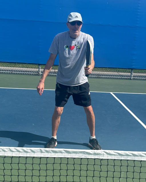 Me standing near net in ready position with paddle up.